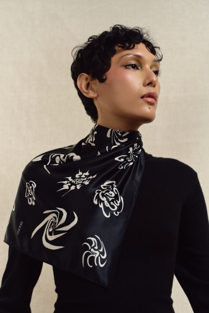 Portrait of a model wearing the black Cyclones square scarf tied at the neck