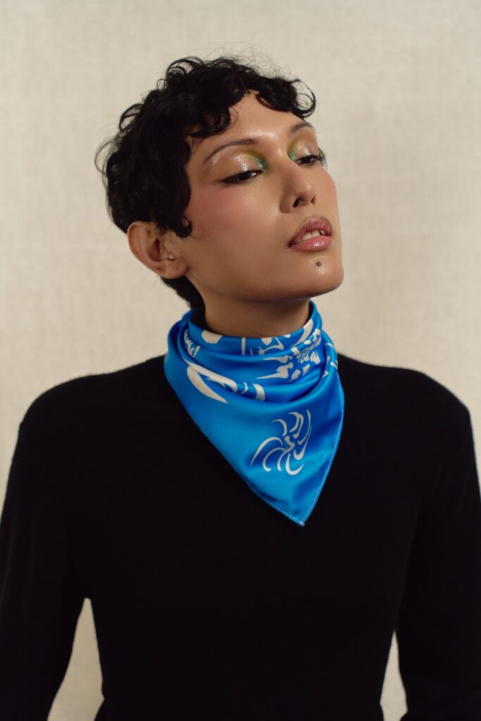 Portrait of a model wearing the blue Cyclones square scarf as a neckerchief