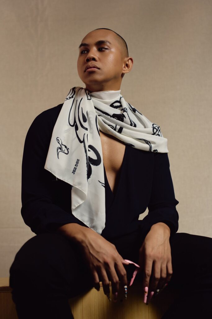 Seated model wearing the Squid long sheer scarf draped around the shoulders