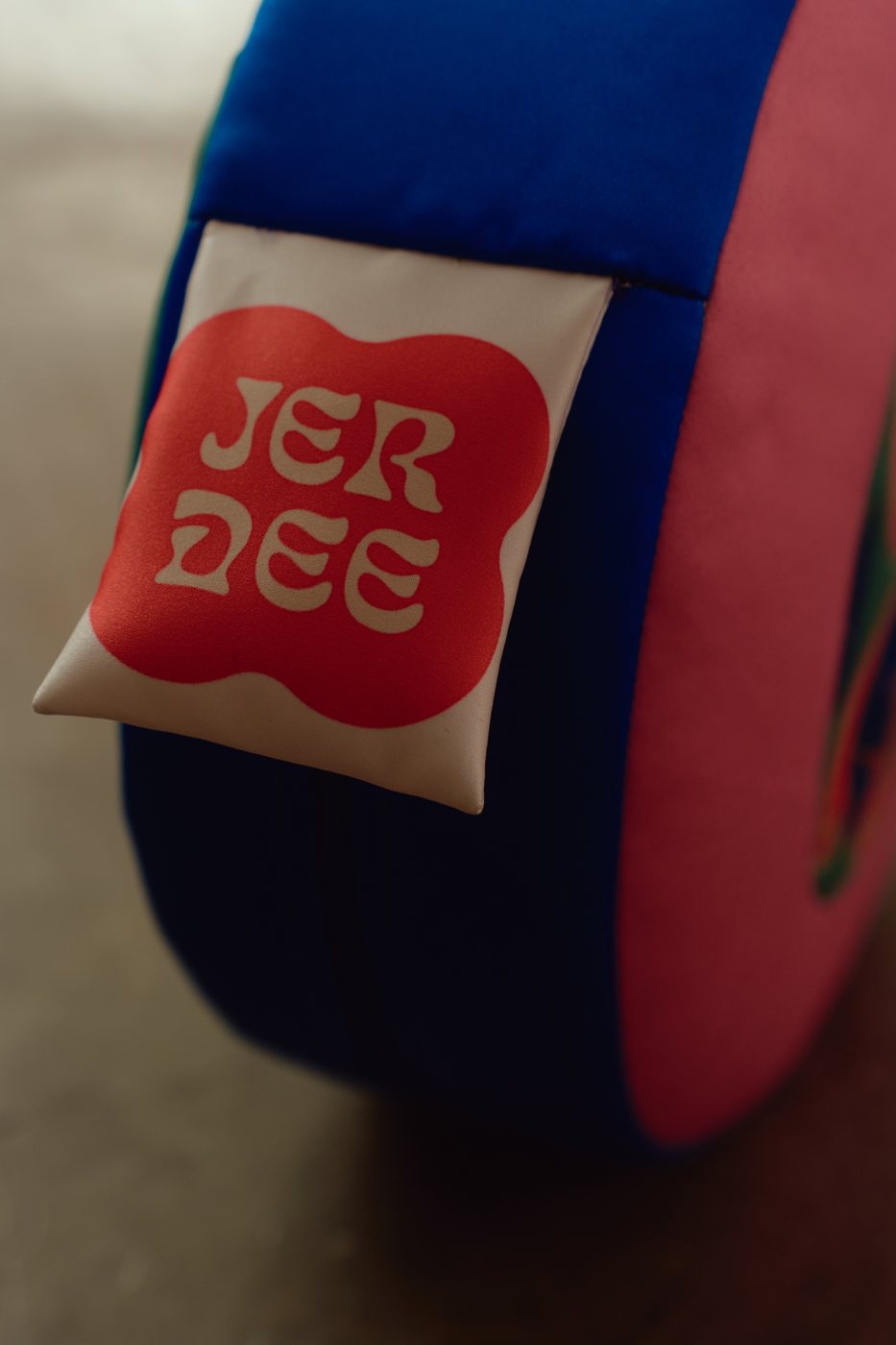 Close-up of a red Jer Dee label sewn on a blue quilted cushion