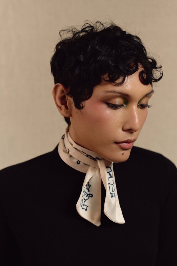 Close portrait of a model wearing the white Motor skinny scarf
