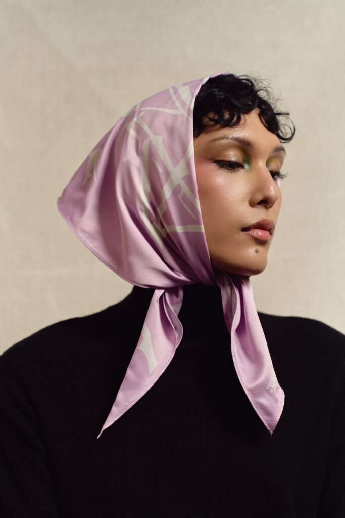 Close portrait of a model in the lavender Solar Village scarf worn as a headscarf